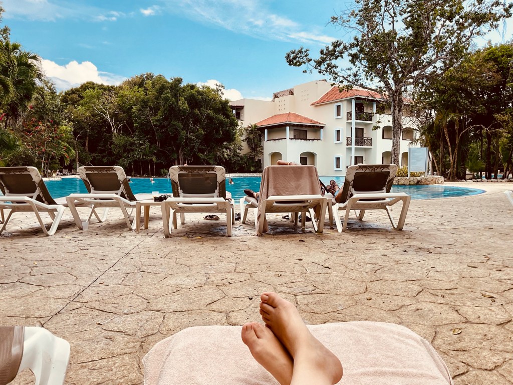 View from lounge chair to pool and palm trees.