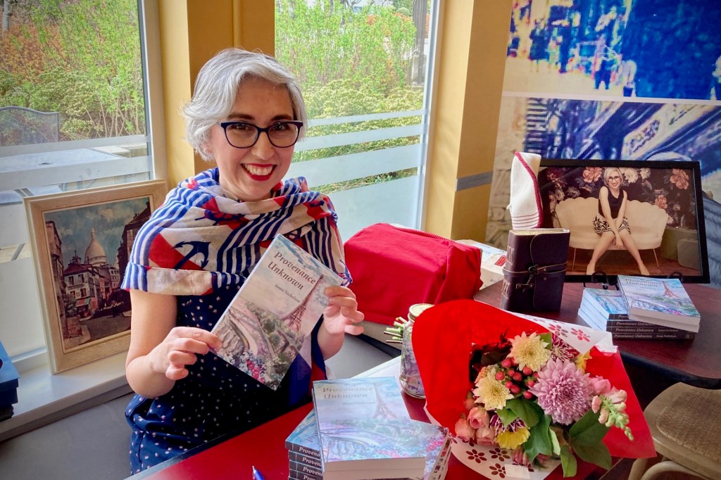 Author Sonia Nicholson holding book Provenance Unknown at French-themed book launch event in 2023.