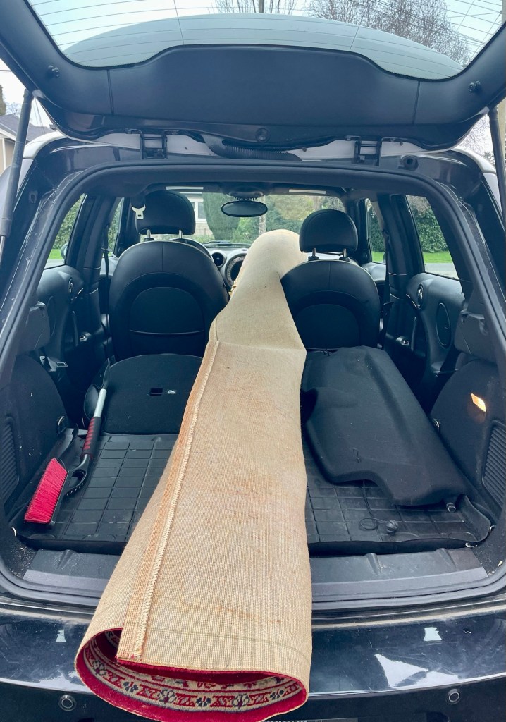 Rolled carpet sticking out of back of car hatch.