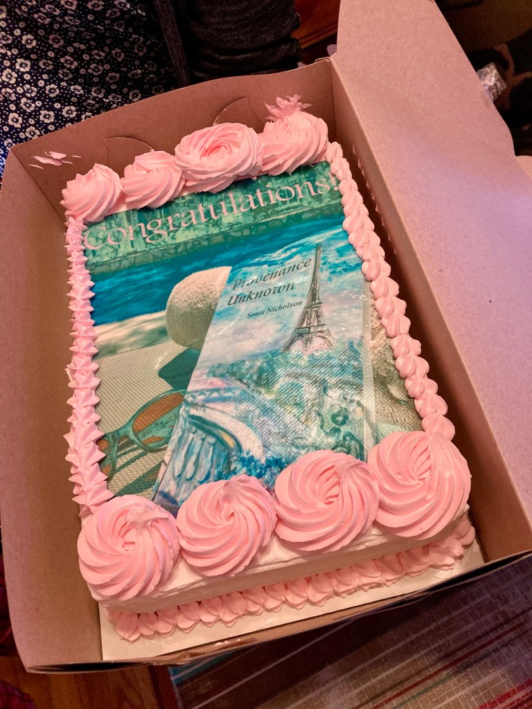 Pink cake with Provenance Unknown by Sonia Nicholson book cover design on top.