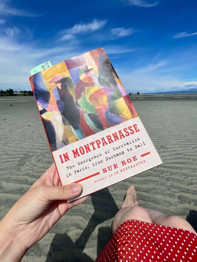 Holding up this book at the beach on a sunny day.